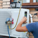 HVAC technician checking an outdoor air conditioner with refrigerant gauges during AC maintenance in Shanty Bay