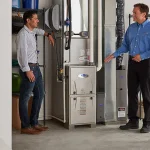 Technician explaining a high-efficiency furnace to two homeowners who are learning how to choose an HVAC company in Barrie