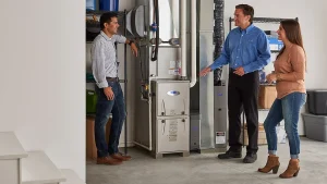 Technician explaining a high-efficiency furnace to two homeowners who are learning how to choose an HVAC company in Barrie